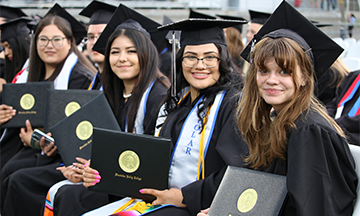 Four graduates holding degrees